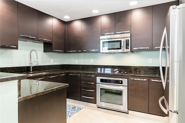 kitchen featuring light tile patterned flooring, sink, dark stone countertops, dark brown cabinetry, and stainless steel appliances