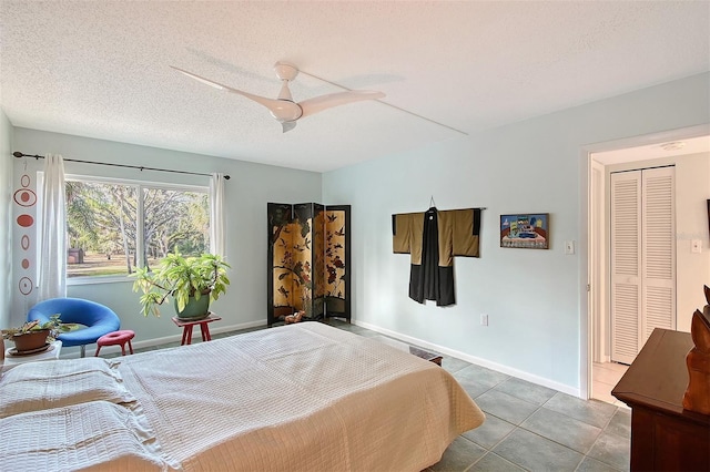 tiled bedroom with ceiling fan, a closet, and a textured ceiling