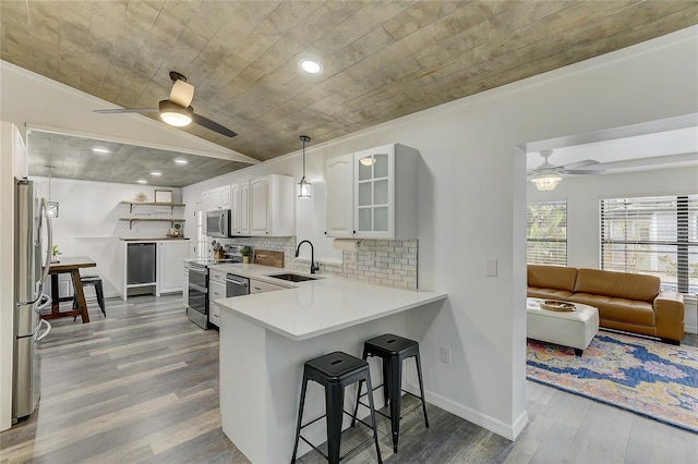 kitchen featuring vaulted ceiling, sink, white cabinets, kitchen peninsula, and stainless steel appliances