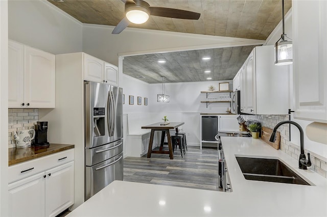 kitchen featuring white cabinetry, stainless steel fridge with ice dispenser, sink, and hanging light fixtures