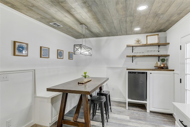 dining room with bar area, wood ceiling, and light wood-type flooring