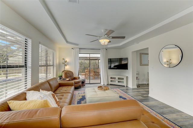 living room with a tray ceiling, wood-type flooring, and ceiling fan