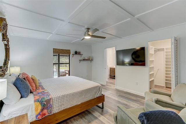 bedroom with coffered ceiling, a spacious closet, a closet, ceiling fan, and hardwood / wood-style floors