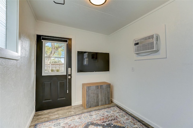 foyer entrance featuring crown molding, light wood-type flooring, and a wall unit AC