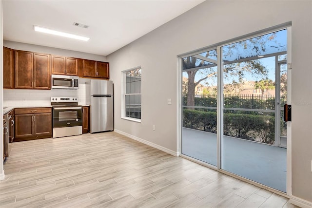 kitchen with stainless steel appliances, decorative backsplash, and light wood-type flooring