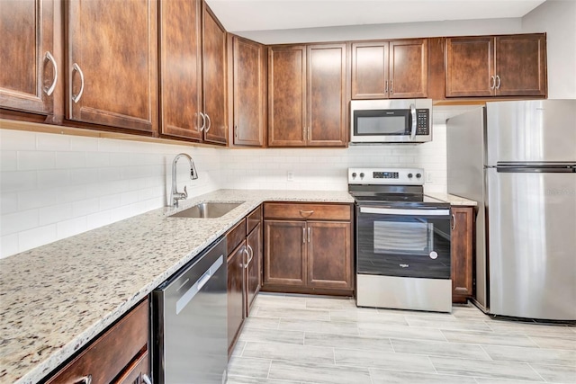 kitchen featuring tasteful backsplash, sink, light stone countertops, and appliances with stainless steel finishes