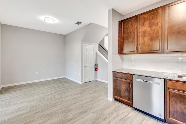 kitchen featuring tasteful backsplash, dishwasher, light stone countertops, and light hardwood / wood-style floors