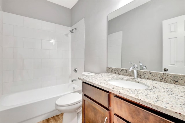 full bathroom featuring vanity, hardwood / wood-style flooring, tiled shower / bath combo, and toilet