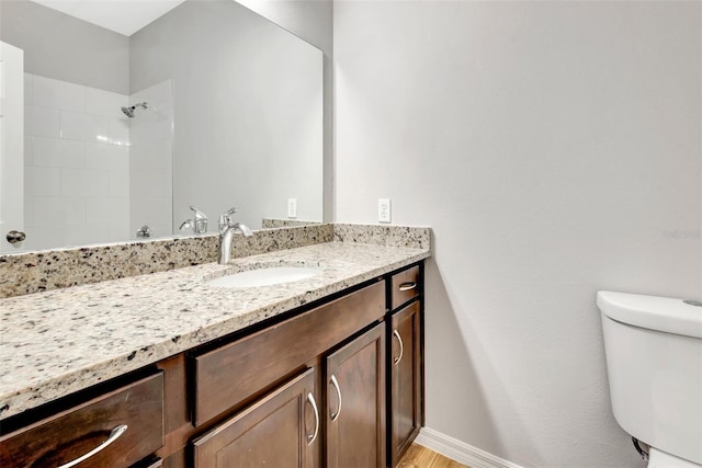 bathroom with vanity, toilet, and a tile shower