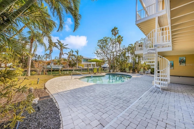 view of pool with a water view and a patio area