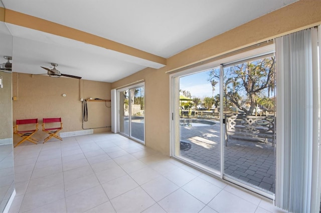 doorway to outside featuring light tile patterned floors, beam ceiling, and ceiling fan