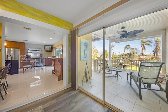 doorway with ceiling fan and light tile patterned floors