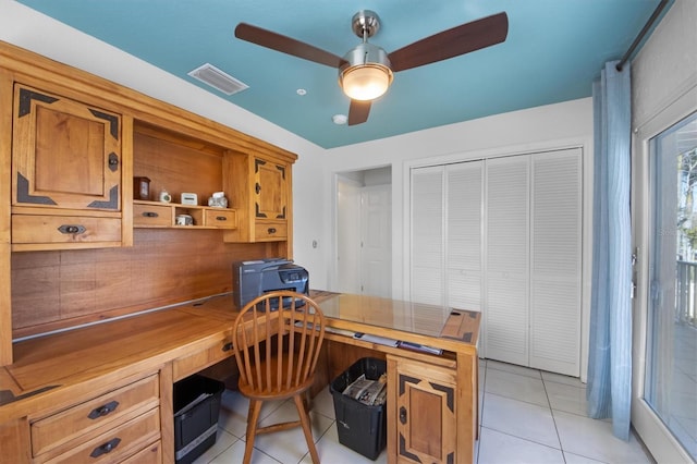 tiled office space with ceiling fan and built in desk