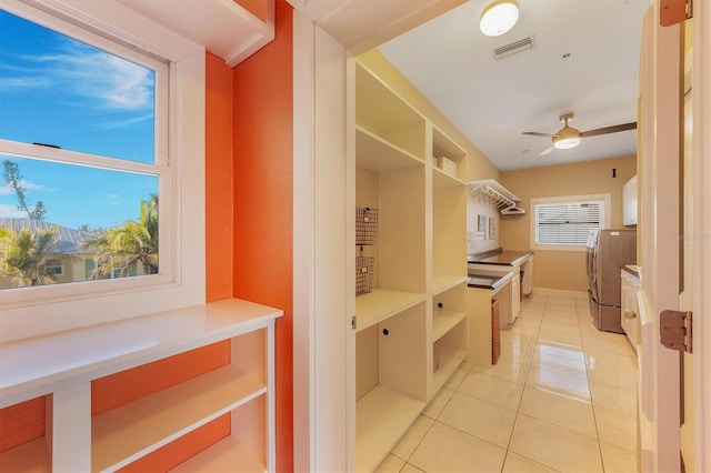 mudroom with ceiling fan, washing machine and dryer, and light tile patterned floors