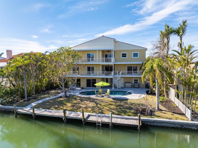 back of house with a water view, a balcony, and a patio area