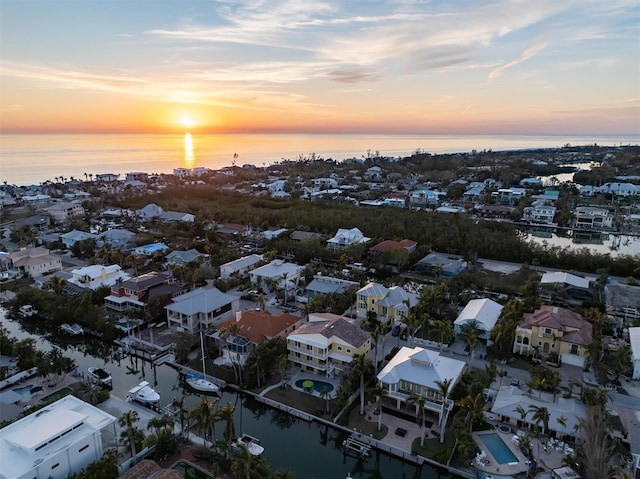 aerial view at dusk featuring a water view