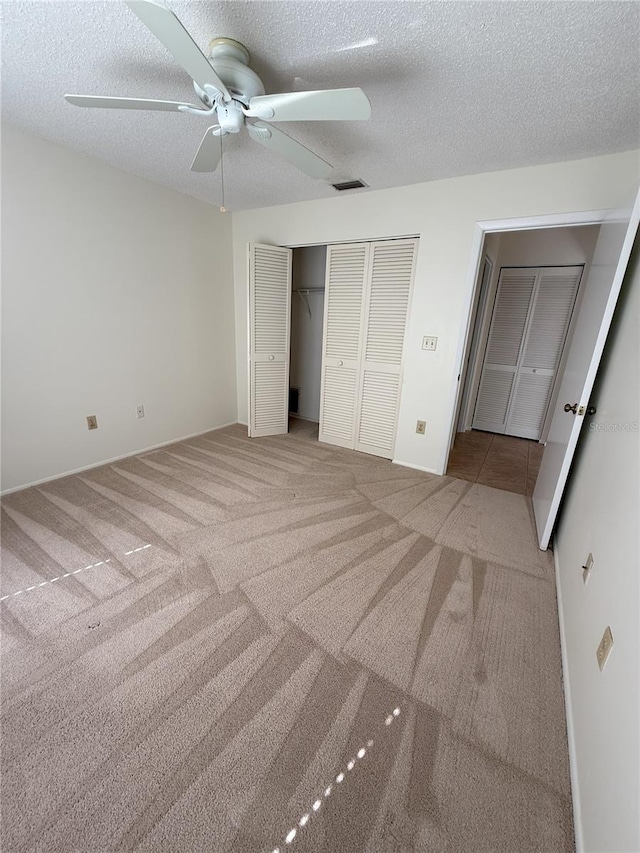 unfurnished bedroom featuring ceiling fan, light carpet, and a textured ceiling