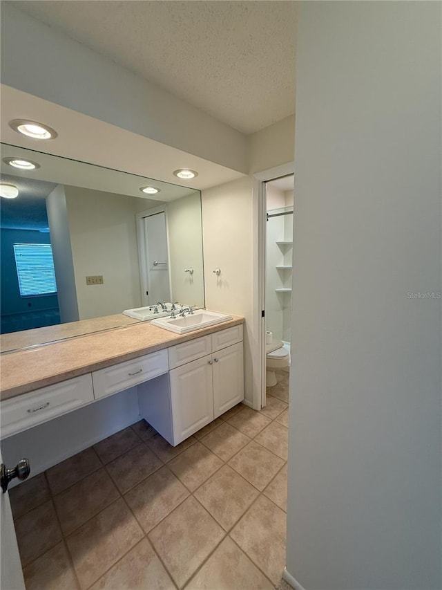 bathroom featuring tile patterned floors, vanity, toilet, and a textured ceiling