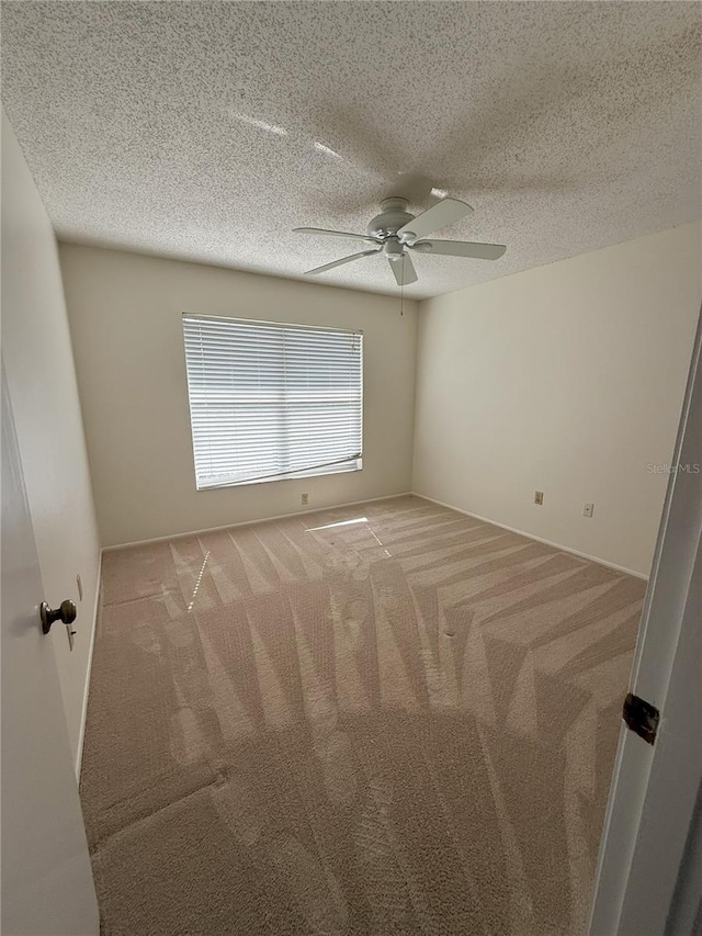 empty room featuring ceiling fan, light colored carpet, and a textured ceiling