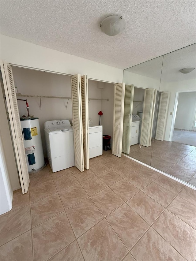 washroom featuring washer / dryer, electric water heater, and light tile patterned floors