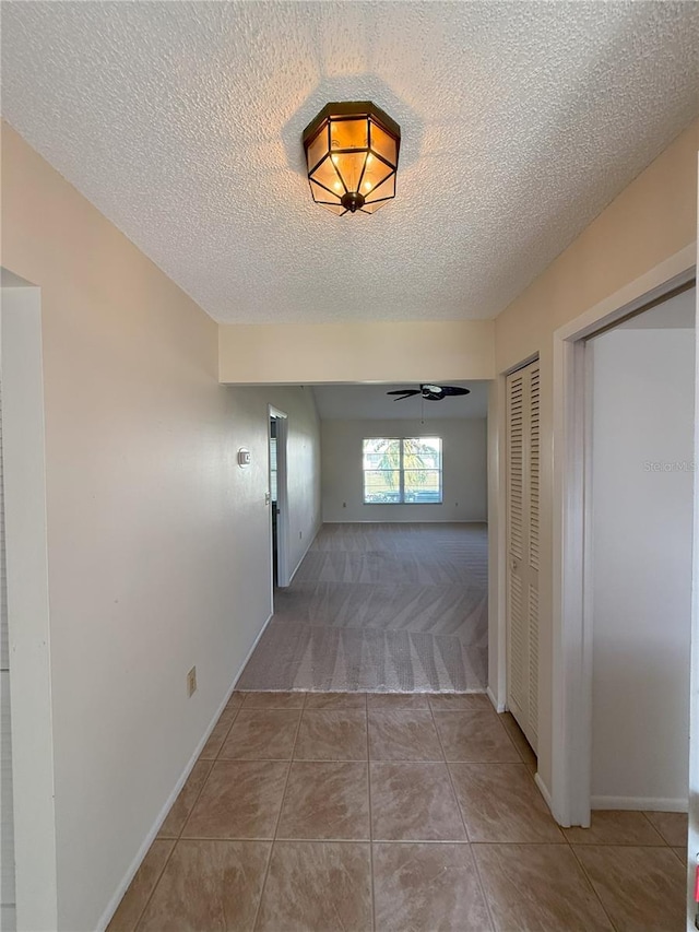 hall with light colored carpet and a textured ceiling