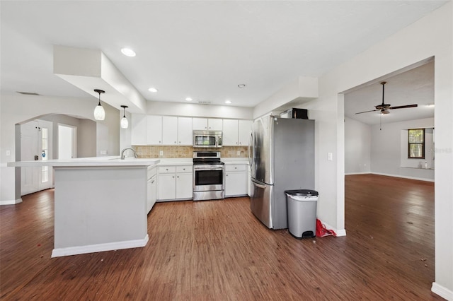 kitchen featuring appliances with stainless steel finishes, white cabinetry, dark hardwood / wood-style flooring, hanging light fixtures, and kitchen peninsula