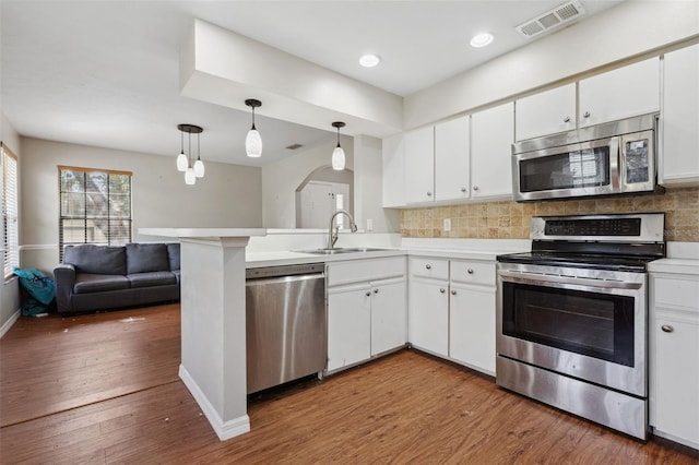 kitchen with pendant lighting, sink, white cabinets, kitchen peninsula, and stainless steel appliances