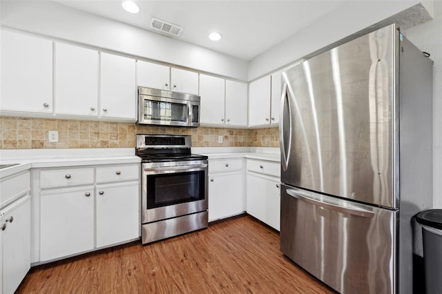 kitchen featuring white cabinetry, hardwood / wood-style flooring, stainless steel appliances, and decorative backsplash