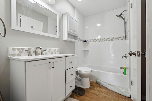 full bathroom with toilet, tasteful backsplash, wood-type flooring, vanity, and tiled shower / bath combo