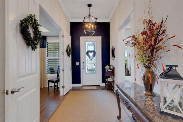 foyer with hardwood / wood-style flooring, crown molding, and an inviting chandelier