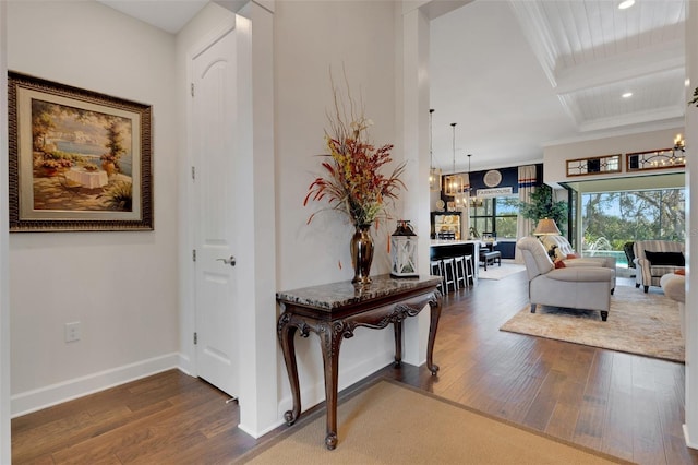 corridor featuring dark wood-type flooring, coffered ceiling, beam ceiling, and a notable chandelier