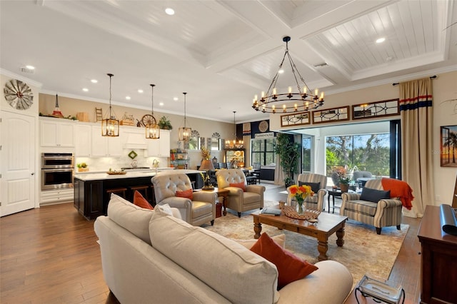 living room featuring an inviting chandelier, hardwood / wood-style floors, ornamental molding, and coffered ceiling