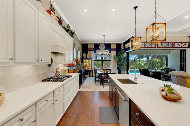 kitchen featuring sink, ornamental molding, stainless steel appliances, and hanging light fixtures