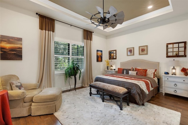 bedroom featuring dark hardwood / wood-style flooring, crown molding, a raised ceiling, and ceiling fan