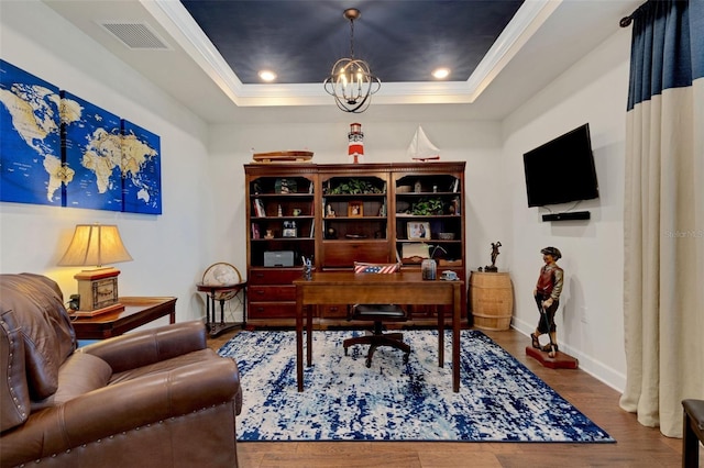 office space with wood-type flooring, ornamental molding, a chandelier, and a tray ceiling