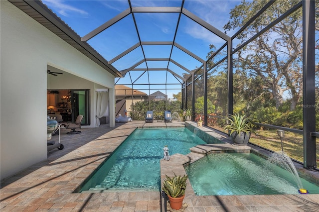 view of pool with ceiling fan, a patio, glass enclosure, pool water feature, and an in ground hot tub