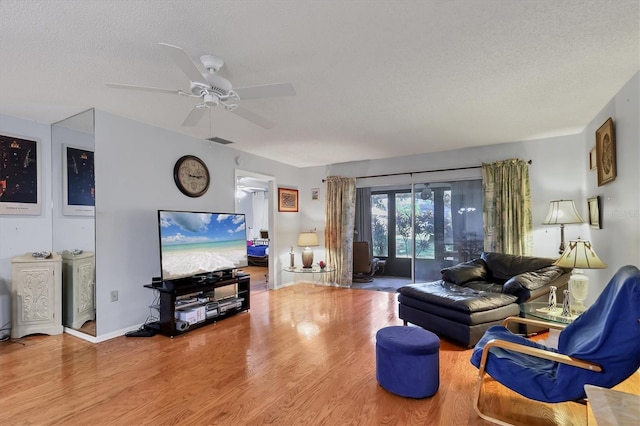 living room with hardwood / wood-style floors, a textured ceiling, and ceiling fan