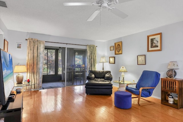 sitting room featuring ceiling fan, wood-type flooring, and a textured ceiling