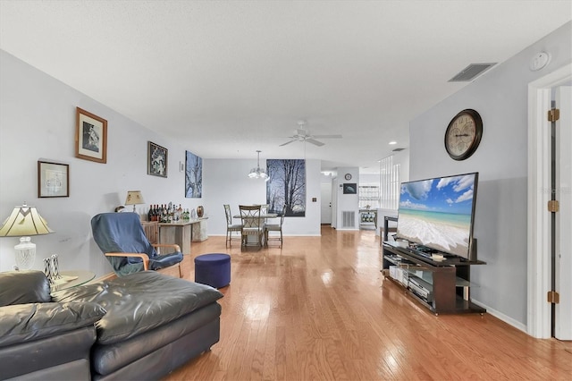 living room with wood-type flooring and ceiling fan with notable chandelier