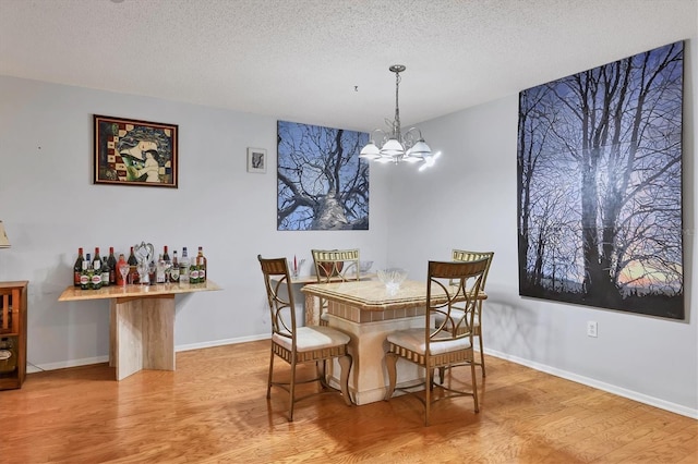 dining space with a notable chandelier, light hardwood / wood-style floors, and a textured ceiling