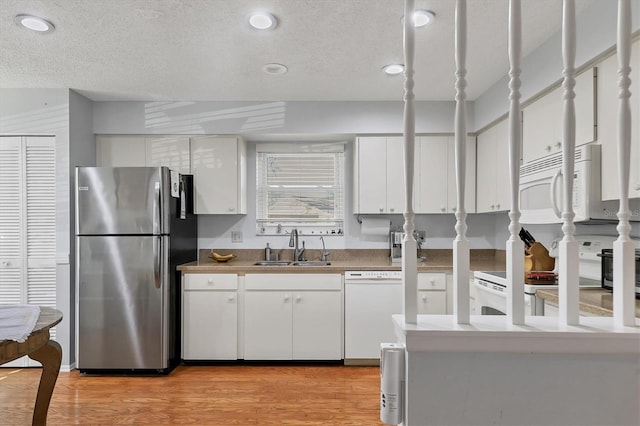 kitchen featuring sink, white appliances, white cabinetry, light hardwood / wood-style floors, and a textured ceiling