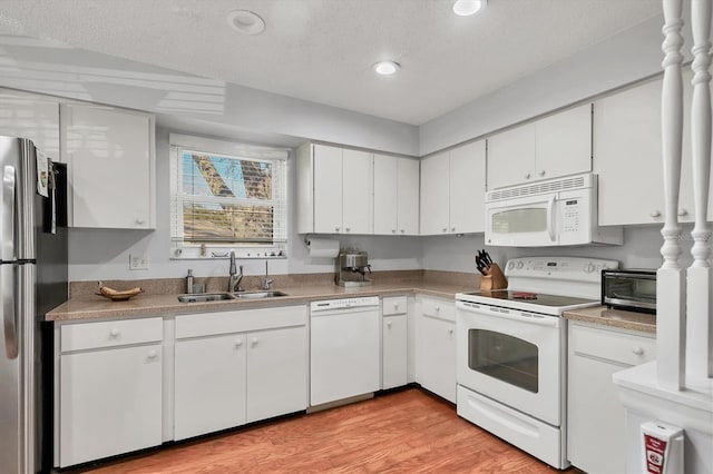 kitchen with white cabinetry, sink, white appliances, and light hardwood / wood-style floors