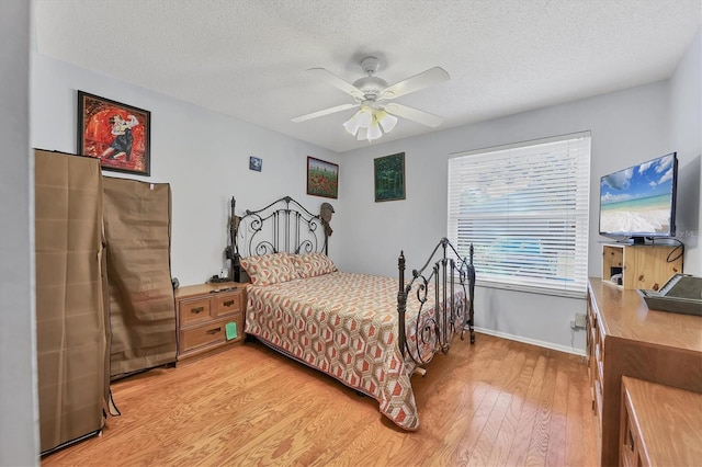 bedroom with a textured ceiling, ceiling fan, and light hardwood / wood-style floors