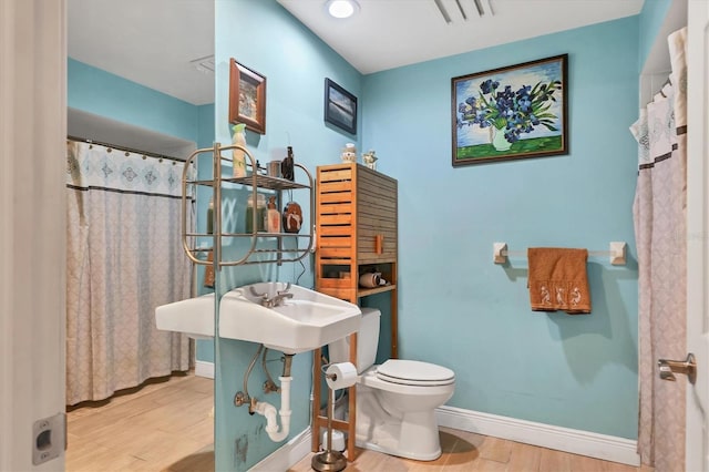 bathroom with hardwood / wood-style floors, a shower with curtain, and toilet