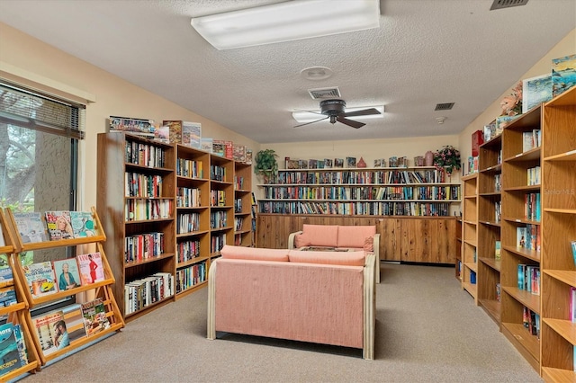 sitting room featuring ceiling fan, light colored carpet, and a textured ceiling