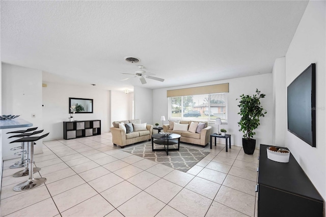 living room featuring ceiling fan, a textured ceiling, and light tile patterned floors