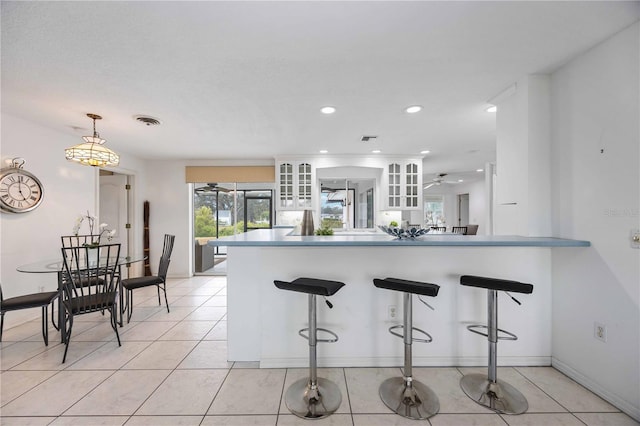 kitchen featuring white cabinetry, light tile patterned floors, decorative light fixtures, and kitchen peninsula