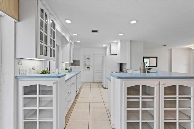 kitchen featuring white refrigerator, light tile patterned floors, sink, and white cabinets