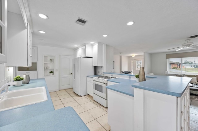 kitchen with sink, white cabinetry, light tile patterned floors, kitchen peninsula, and white appliances