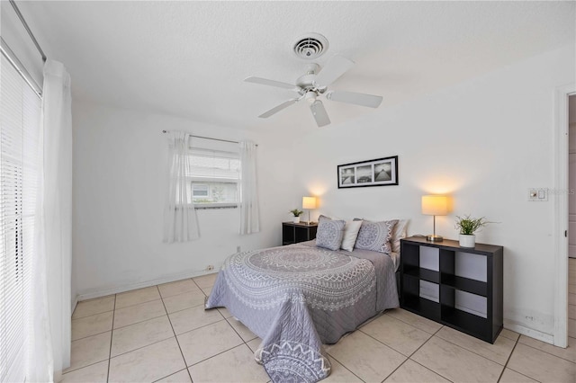 bedroom with light tile patterned flooring, ceiling fan, and a textured ceiling